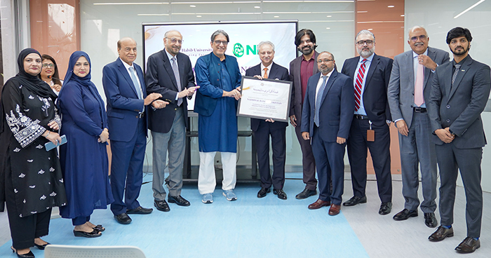Group photo: Habib University and National Bank of Pakistan leaders hold a framed certificate after signing the scholarship MoU in Karachi.