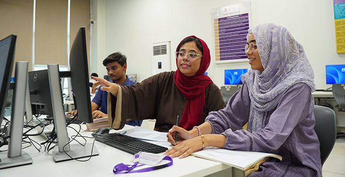 a girl showing another girl something in the computer