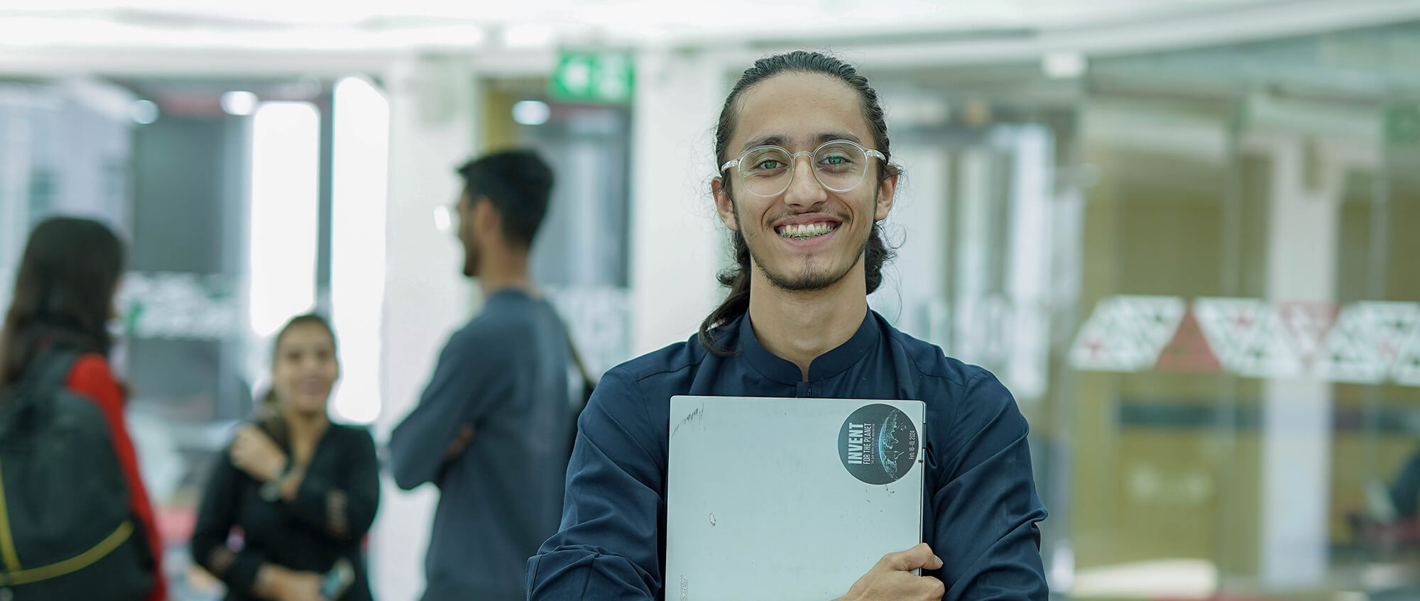 a boy looking towards the camera while holding a laptop